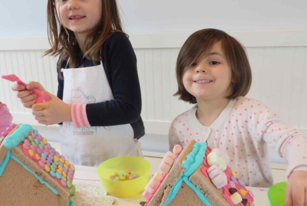 Two children making cookies and gingerbread houses during a kids cooking summer camp