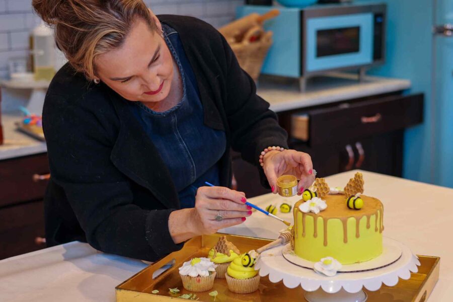 Mrs. FrogLegs decorating a honey-bee cake and cupcakes